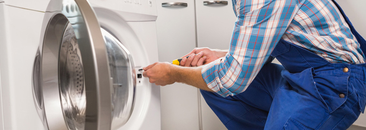 A repair man fixing a clothes dryer